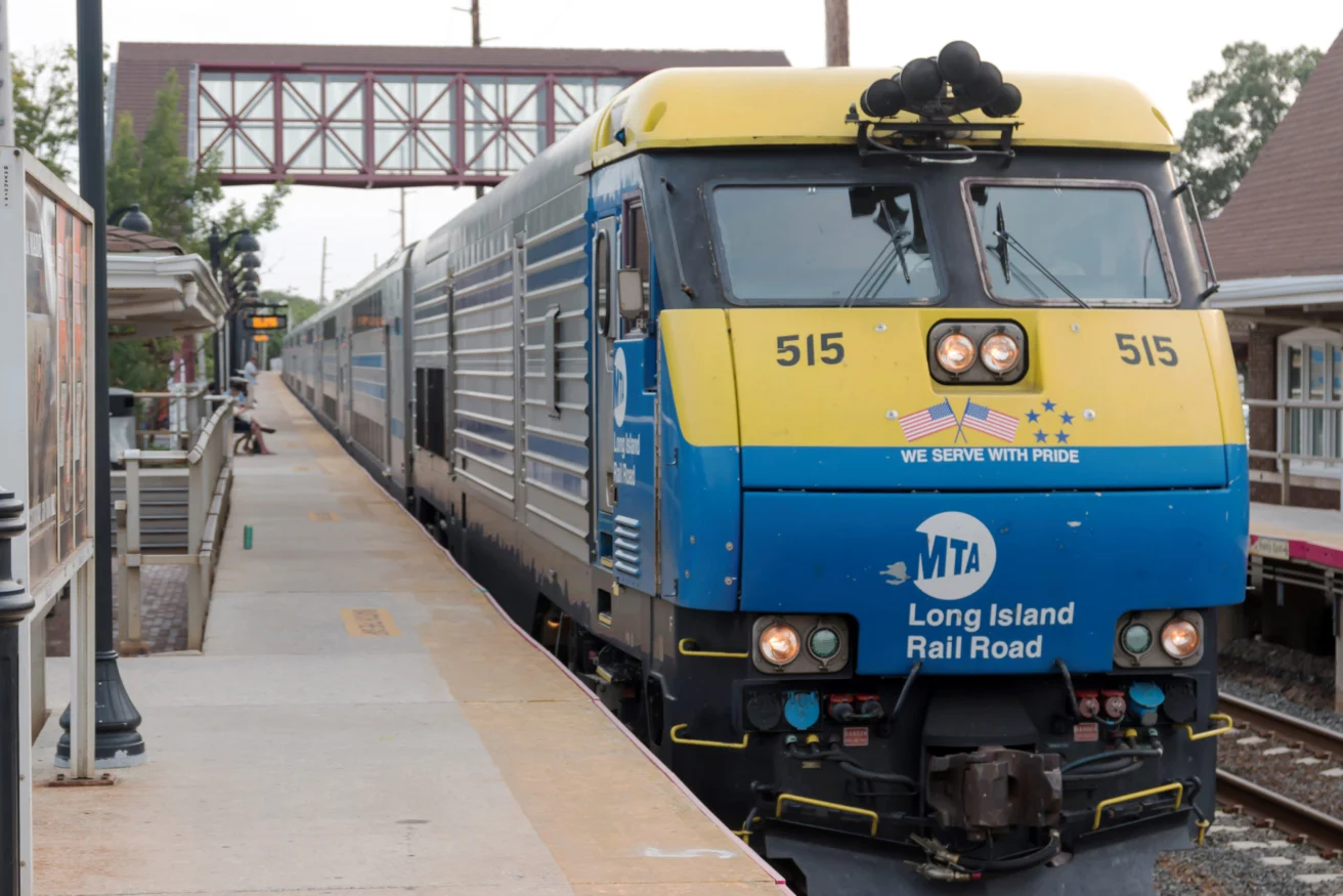 A Long Island Rail Road train with a blue and yellow engine numbered 515 is stopped at a station platform.