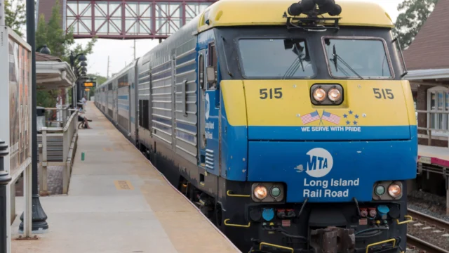 A Long Island Rail Road train with a blue and yellow engine numbered 515 is stopped at a station platform.