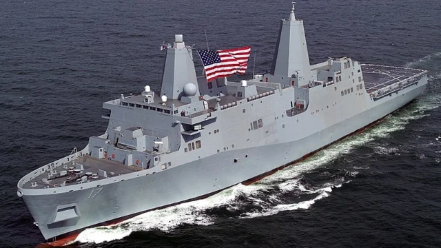 Gray warship sailing on the sea, flying a large American flag.
