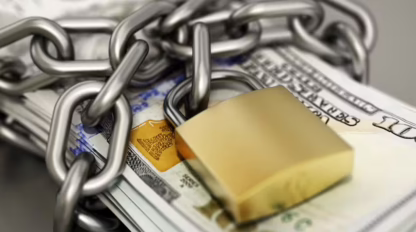 Stack of U.S. hundred-dollar bills wrapped in a thick chain and secured with a gold padlock.